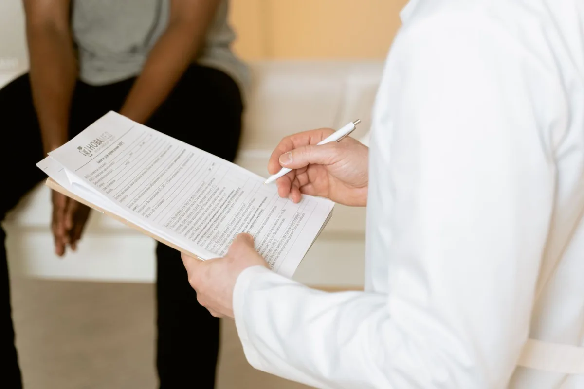 A healthcare professional reviewing a medical form during a patient consultation. Stock photo.